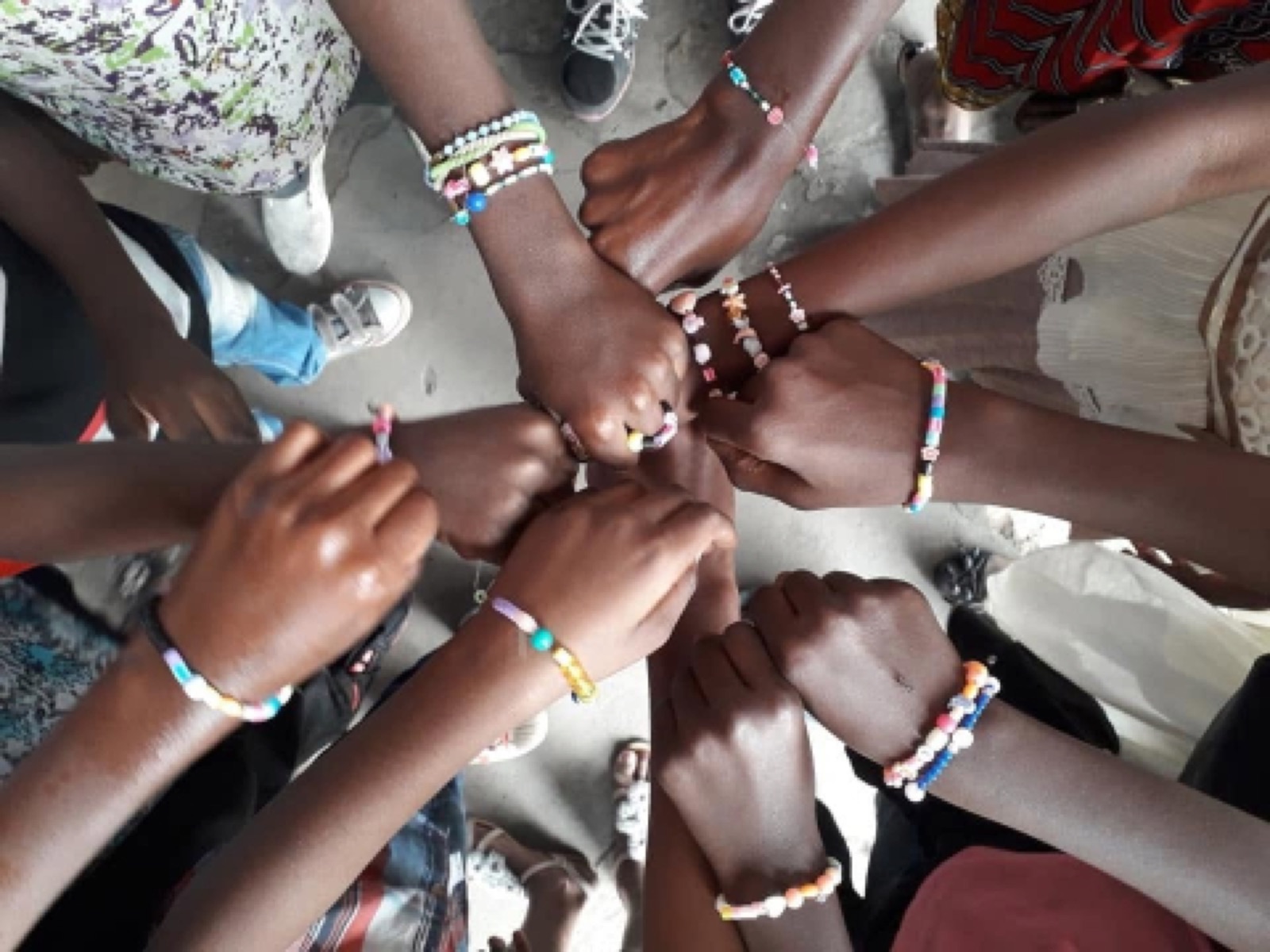 Hands meeting in the centre, wearing handmade beaded bracelets